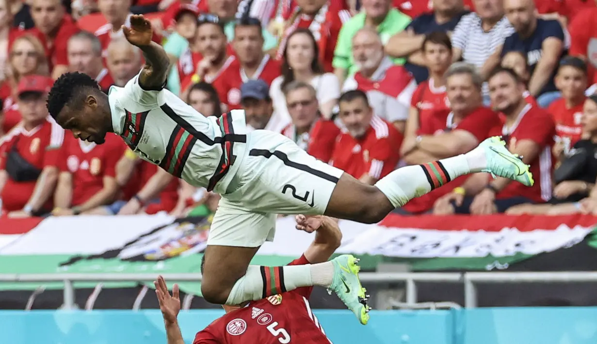 Bek Portugal, Nelson Semedo( atas) saat berebut bola dengan pemain Hungaria, Attila Fiola pada pertandingan grup F Euro 2020 di stadion Ferenc Puskas di Budapest, Hungaria, Selasa (15/6/2021). Portugal menang atas Hungaria 3-0. (Bernadett Szabo/Pool via AP)