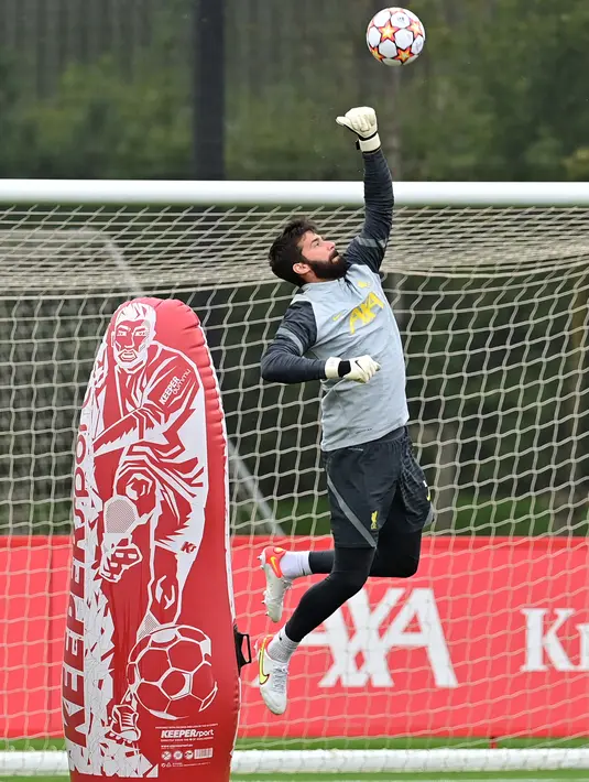 Penjaga gawang Liverpool, Alisson Becker menepis bola saat sesi latihan di pusat pelatihan Axa di Kirkby, Liverpool, Inggris (14/9/2021). Liverpool akan bertanding melawan wakil Italia, AC Milan pada Grup B Liga Champions di Anfield. (AFP/Paul Ellis)