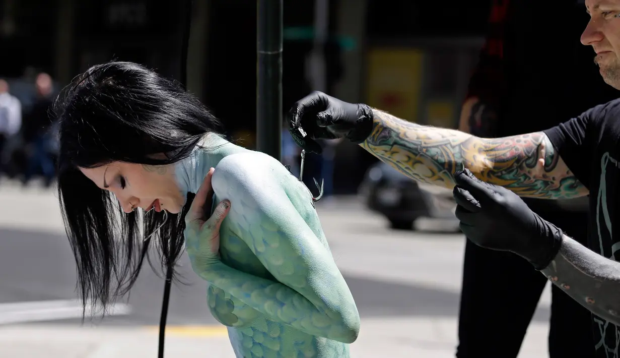 Tim mengait punggung Victoria Lemeow jelang aksi menolak penangkapan ikan di Seattle, AS, Senin (5/6). Aksi yang disponsori PETA  ini sebagai protes terhadap SeaWeb Seafood Summit yang diadakan di kawasan tersebut. (AP Photo / Elaine Thompson)