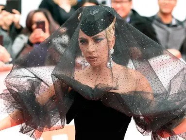 Lady Gaga berpose di karpet merah saat tiba menghadiri pemutaran film "A Star is Born" selama Toronto International Film Festival 2018 di Toronto (9/9). Lady gaga tampil menggenakan gaun berwarna hitam. (AP Photo/Nathan Denette)