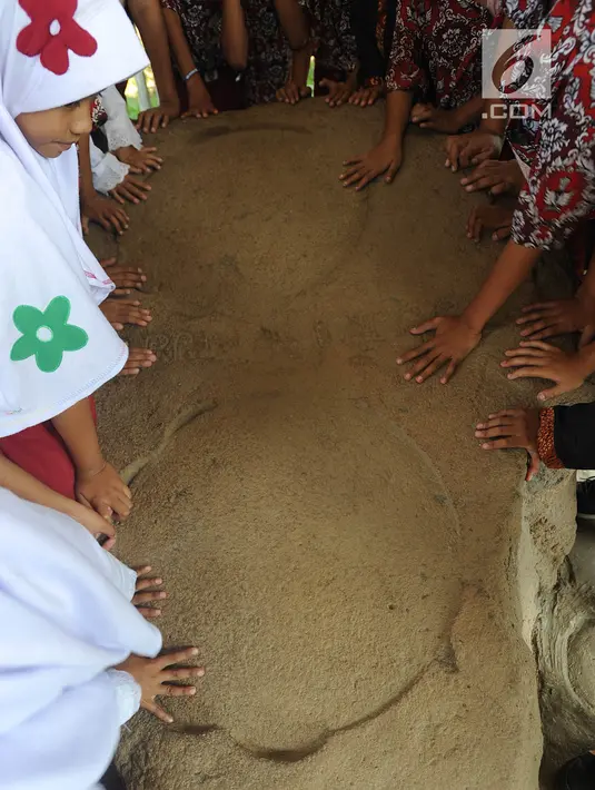 Murid SD melihat prasasti telapak kaki gajah di Prasasti Kebun Kopi, Ciaruteun Ilir, Bogor, Jawa Barat, Rabu (15/8). Prasasti ini peninggalan budaya Kerajaan Tarumanegara yang berdiri pada abad 4 hingga 7 masehi di Pasundan. (Merdeka.com/Arie Basuki)