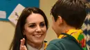 Kate Middleton tos dengan seorang anak setelah berhasil membuat rekayasa pemberian pertolongon pertama dalam acara Cub Scout Pack di Kings Lynn, Inggris (14/12). (Reuters/Ben Stansall/Pool) 