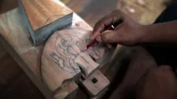 Seorang pengrajin kayu dari komunitas etnis Newar membuat sketsa diatas kayu sebelum diukir di Lalitput, Nepal (19/7). Komuitas pengrajin kayu ini memulai aktivitas sosialnya sejak dua tahun lalu. (AP Photo/Niranjan Shrestha)