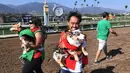 Rick Garcia bersama anjingnya 'Roi' keluar sebagai juara dalam kejuaraan "Corgi Nationals" California Selatan di Arena Balap Santa Anita di Arcadia pada 26 Mei 2019. Ratusan anjing corgi yang mengikuti kejuaraan ini memperebutkan gelar anjing tercepat. (Photo by Mark RALSTON / AFP)