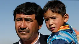 Murtaza Ahmadi digendong oleh ayahnya saat berada di markas Federasi Sepak Bola Afghanistan di Kabul, (2/2). Ahmadi  merupakan penggemar berat dari pemain internasional Argentina tersebut. (REUTERS / Omar Sobhani)
