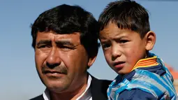 Murtaza Ahmadi digendong oleh ayahnya saat berada di markas Federasi Sepak Bola Afghanistan di Kabul, (2/2). Ahmadi  merupakan penggemar berat dari pemain internasional Argentina tersebut. (REUTERS / Omar Sobhani)