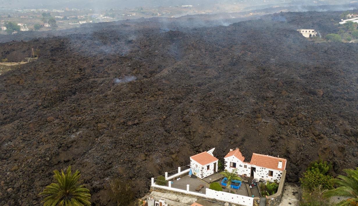 Lava dari letusan gunung Cumbre Vieja mengalir menghancurkan rumah-rumah di pulau La Palma di Canaries, Spanyol, Selasa (21/9/2021). Diketahui gunung berapi ini merupakan salah satu daerah vulkanik paling aktif di Canaries dan pernah mengalami letusan besar pada tahun 1971. (AP/Emilio Morenatti)