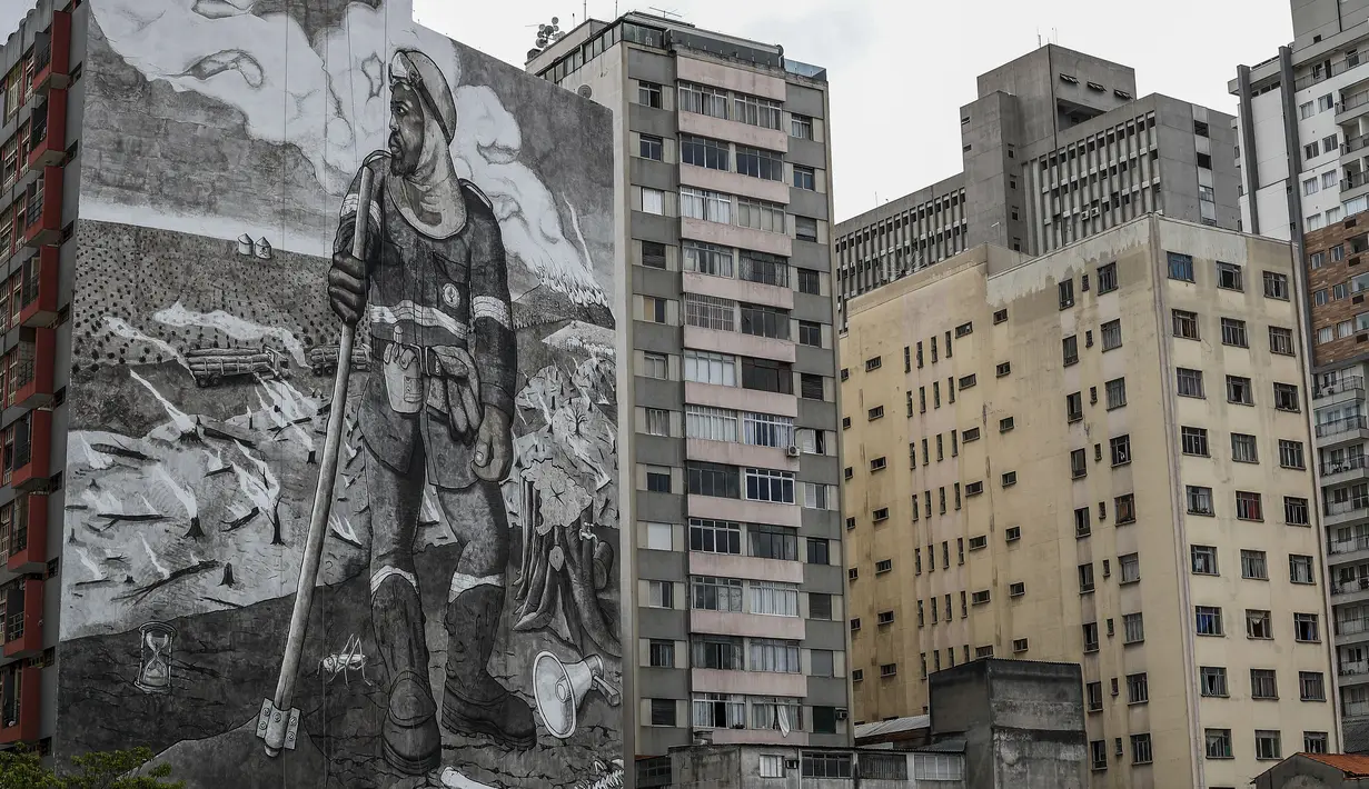 Mural berjudul "The Forest Brigadir" menggunakan abu kebakaran hutan Amazon oleh seniman Thiago Mundano, menutupi kompleks apartemen di Sao Paulo, Brasil, Jumat (15/10/2021). Mural bergambar petugas damkar yang berdiri di tengah peristiwa deforestasi, kebakaran, dan hewan mati. (AP/Marcelo Chello)