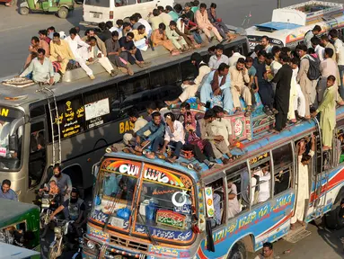 Sejumlah penumpang duduk di atas atap bus saat mudik menuju kampung halaman untuk merayakan Idul Adha di Lahore, Pakistan, Sabtu (10/8/2019). Umat Islam di seluruh dunia merayakan Idul Adha yang identik dengan tradisi berkurban. (Photo by ARIF ALI / AFP)