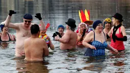 Anggota klub renang es "Berliner Seehunde" merayakan tahun baru dengan berenang di danau Orankesee, Berlin, Jerman (1/1). Selain berenang mereka juga bermain air sambil menyalakan kembang api. (REUTERS/Fabrizio Bensch)