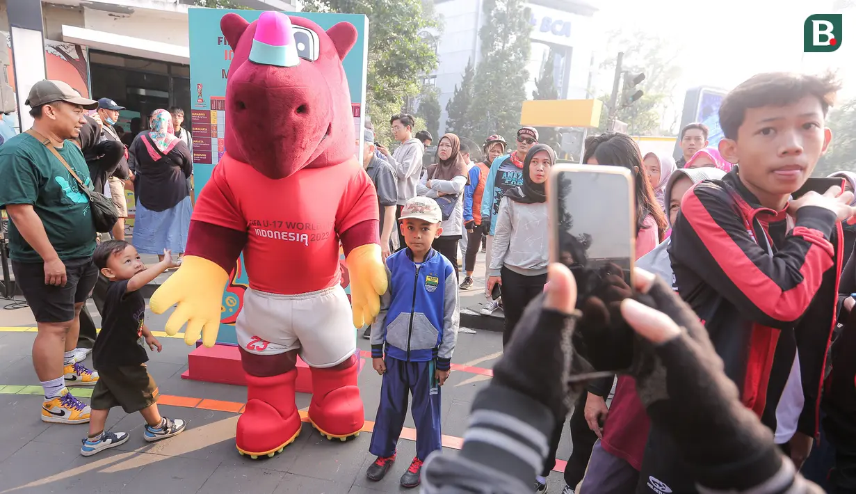 Seorang pengunjung cilik berfoto bareng dengan maskot Piala Dunia U-17 2023, Bacuya dalam rangkaian acara Trophy Tour Experience menyambut Piala Dunia U-17 di Cikapayang Dago Park, Bandung, Minggu (22/10/2023) pagi WIB. (Bola.com/Bagaskara Lazuardi)