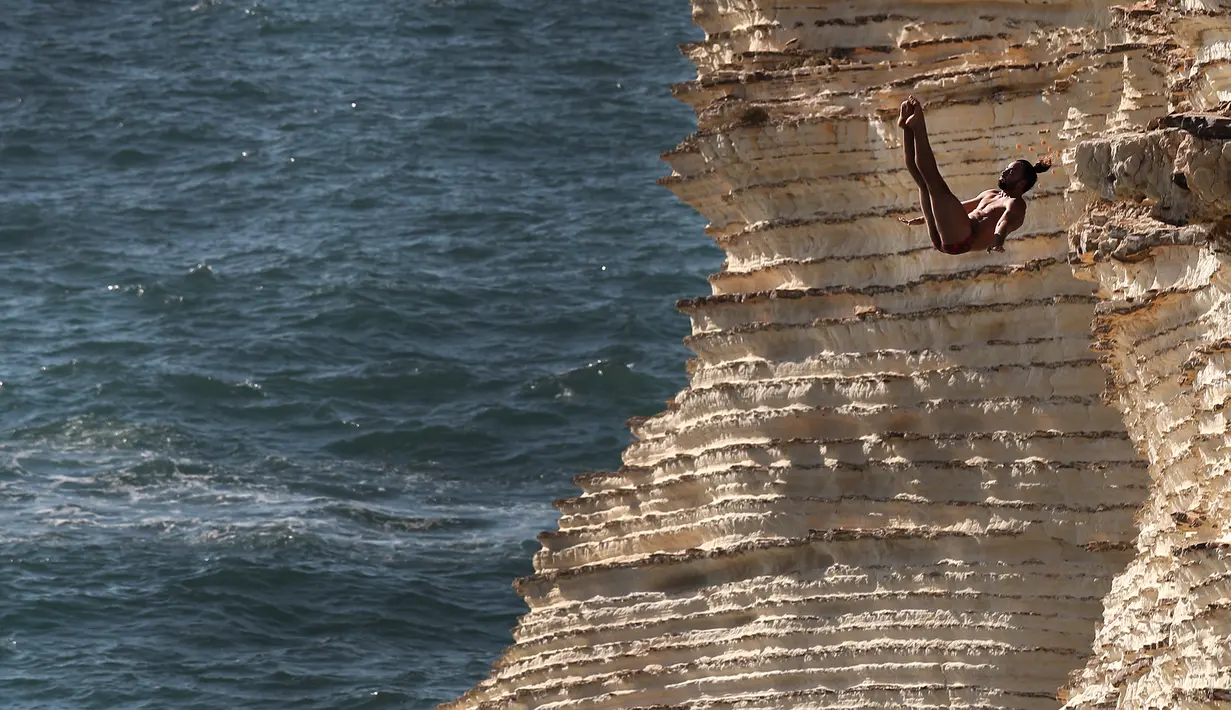 Peserta melompat dari batu karang laut 'Raouche' yang terkenal dalam kompetisi Red Bull Cliff Diving World Series di Beirut, Lebanon, 14 Juli 2019. Sebanyak 40 atlet terdiri dari 10 wanita dan 14 pria yang berasal dari 18 negara melakukan lompatan dari ketinggian 21 - 27 meter. (AP/Hussein Malla)