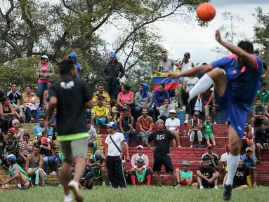 Para migran Venezuela bermain sepak bola di kamp sementara di Bogota, Kolombia (21/11). Pejabat kota menyelenggarakan turnamen sepak bola bagi migran yang tinggal di kamp yang dibangun badan kesejahteraan sosial kota tersebut. (AP Photo/Ivan Valencia)