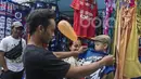 Seorang bapak mencobakan anaknya baju yang dijual oleh pedagang kaki lima jelang laga semifinal Piala Presiden 2017 antara Arema FC melawan Semen Padang di sekitar Stadion Kanjuruhan, Malang, Jawa Timur, Minggu (5/3/2017). (Bola.com/Vitalis Yogi Trisna)