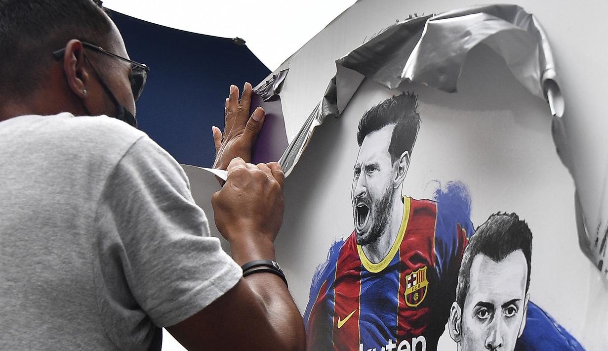 Pekerja melepas poster yang menampilkan pemain depan Argentina, Lionel Messi di pintu masuk Stadion Camp Nou, Barcelona pada Selasa, 10 Agustus 2021. Lionel Messi resmi meninggalkan Barcelona akibat masalah finansial klub dan peraturan dari Liga Spanyol. (AFP/Pau Barrena)
