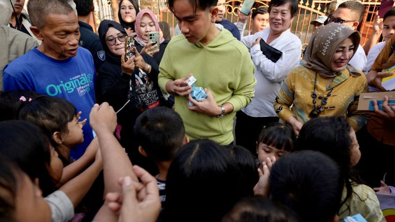 Wakil Presiden terpilih RI, Gibran Rakabuming Raka melakukan blusukan di sebuah permukiman di Jakarta, pada Rabu (3/7/2024). Dalam kesempatan tersebut, Gibran membagi-bagikan buku dan susu gratis kepada anak-anak yang ditemuinya. Foto: Bay Ismoyo/AFP