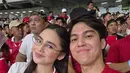 El Rumi dan Syifa Hadju pilih kombinasi jersey yang melambangkan bendera Merah Putih. Syifa Hadju kenakan jersey putih dengan celana cokelat dan tas Chanel Flap Bag. Sedangkan El Rumi tampil kasual dengan jersey merah [@elelrumi]