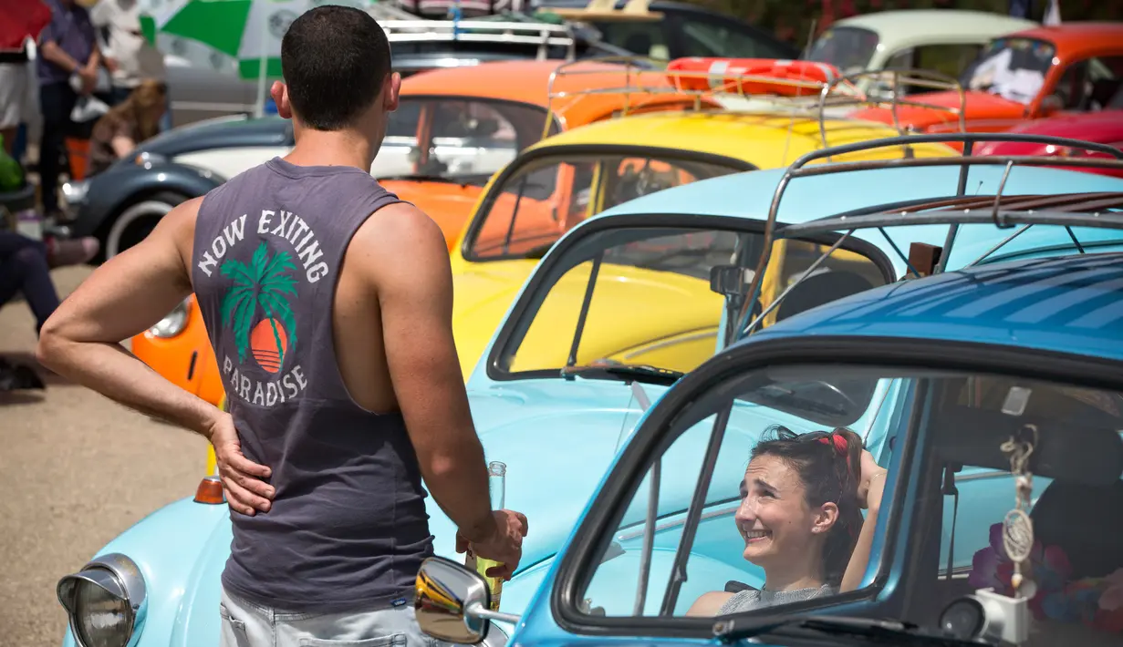 Peserta berbincang saat mengikuti ajang pertemuan tahunan "Beetle club" di Yakum, Israel tengah (21/4). Volkswagen Beetle ini diproduksi mulai tahun 1938 sampai 2003, dengan bentuk yang khas. (AP Photo / Oded Balilty)