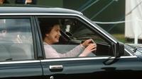 Ratu Elizabeth II melempar senyum kepada warga Inggris saat mengemudi sebuah sedan (townandcountrymag.com)