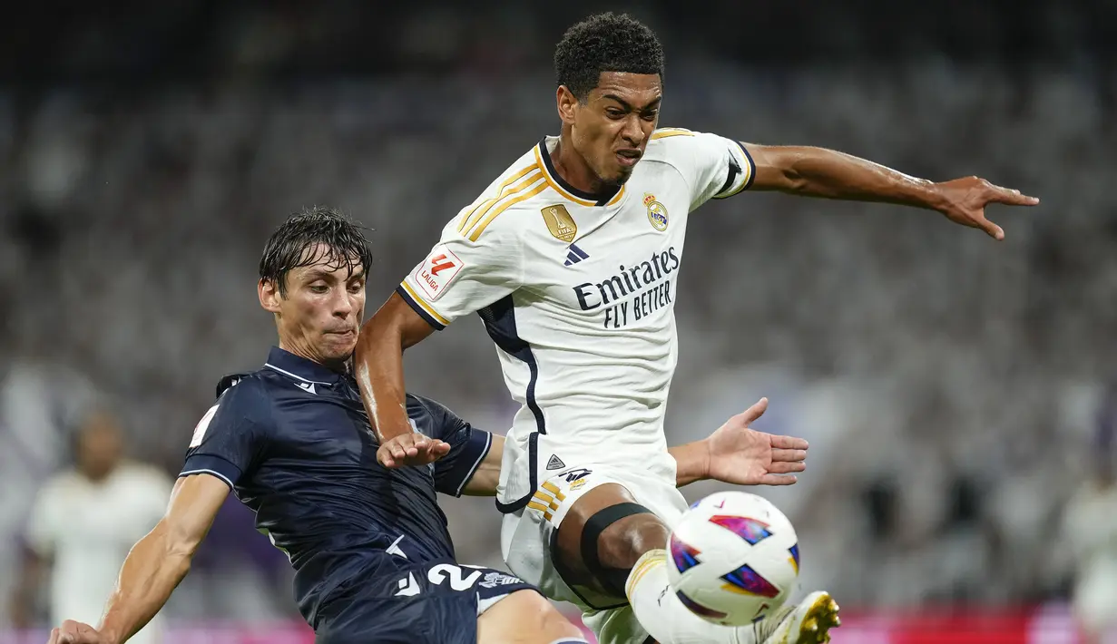 Gelandang Real Madrid, Jude Bellingham (kanan) berebut bola dengan bek Real Sociedad Robin Le Normand pada laga pekan kelima Liga Spanyol 2023/2024 di Santiago Bernabéu Stadium, Madrid, Senin (18/9/2023) dini hari WIB. (AP Photo/Jose Breton)