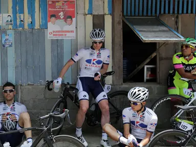 Para pebalap sepeda beristirahat sebelum melakukan start ulang di Titik Nol Kilometer Painan, Kabupaten Pesisir Selatan, Sumatra Barat saat Etape 1 Tour de Singkarak, Sabtu (3/10/2015). (Bola.com/Arief Bagus)