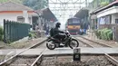 Pengendara motor melintasi palang pintu kereta di pintu pelintasan Kalibata, Jakarta, (4/12). Untuk menekan angka kecelakaan, Pemprov DKI Jakarta berencana membangun flyover diperlintasan kereta api. (Liputan6.com/Yoppy Renato)