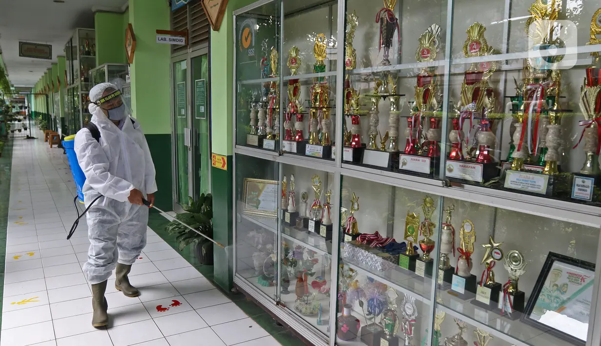 Petugas melakukan penyemprotan cairan disinfektan jelang dibukanya pembelajaran tatap muka di SMK PB Soedirman 2, Jakarta, Selasa (6/4/2021). Uji coba pembelajaran tatap muka akan dilakukan di 5 madrasah, 1 PKBM, 42 SD, 13 SMP, 9 SMA, dan 30 SMK. (Liputan6.com/Herman Zakharia)