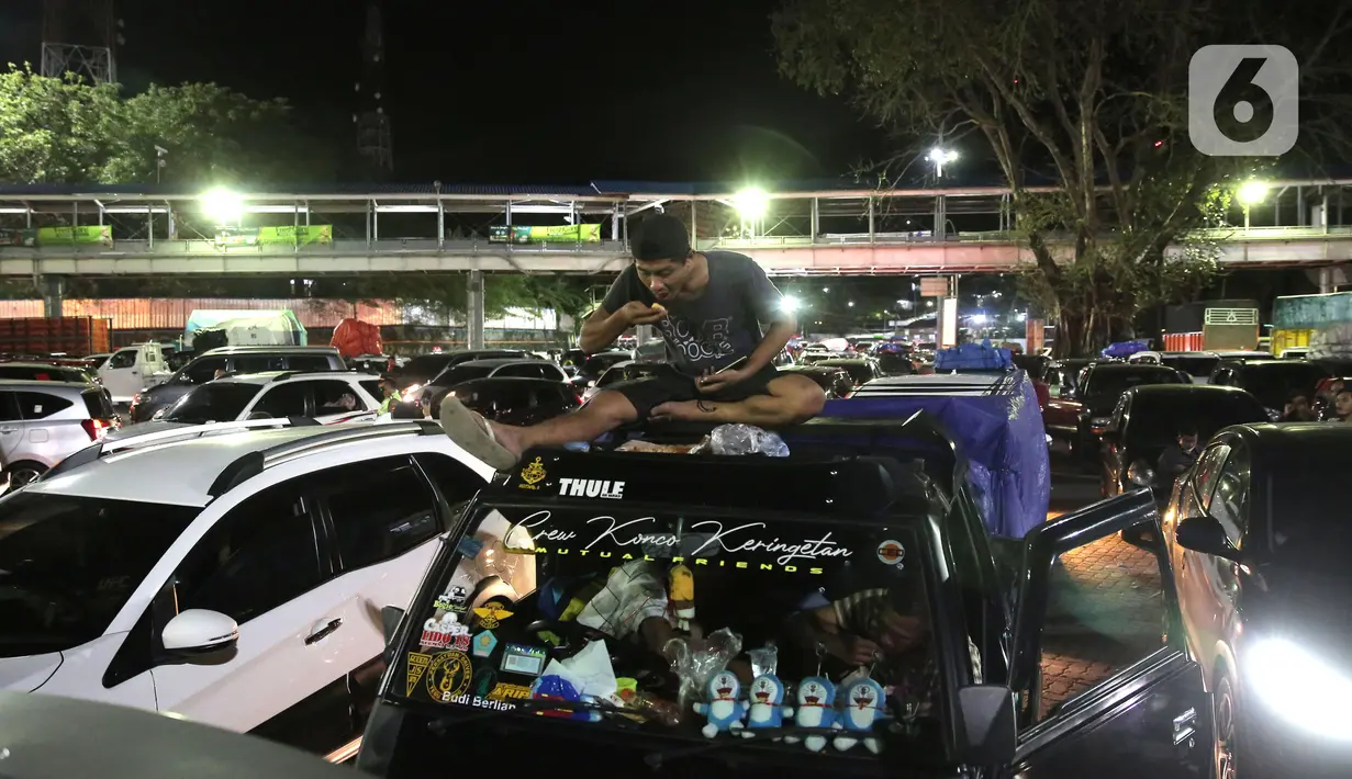 <p>Seorang pria menikmati makanan di atas mobil sambil menunggu antrean memasuki kapal "Roll on-Roll off" (RoRo) di Pelabuhan Merak, Banten, Kamis (28/4/2022). Jelang hari raya Idul Fitri, pemudik dengan kendaraan bermotor mulai memadati Pelabuhan Merak. Penumpukan kendaraan ini menyebabkan terjadinya antrean kendaraan yang panjang. (Liputan6.com/Angga Yuniar)</p>