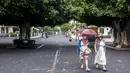 Orang-orang berjalan di jalan yang tertutup abu dari gunung berapi di Pulau Canary La Palma, di Los Llanos de Aridane, Spanyol (1/10/2021). Pihak berwenang tengah mengawasi untuk melihat apakah lava dari celah baru akan bergabung dengan aliran utama yang telah mencapai laut. (AP Photo/Saul Santos)
