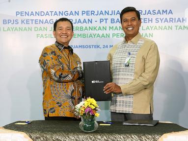 Direktur Utama BPJS Ketenagakerjaan (BPJAMSOSTEK) Anggoro Eko Cahyo (kanan) dan Direktur Utama Bank Aceh Haizir Sulaiman (kiri) menunjukkan naskah Perjanjian Kerja Sama dalam Rangka Pemberian Manfaat Layanan Tambahan (MLT) di Plaza BPJAMSOSTEK Jakarta, Kamis (24/03/2022). (Liputan6.com/Fery Pradolo)