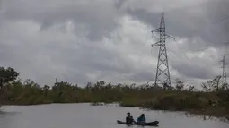 Warga menyeberangi banjir dengan sampan yang disebabkan oleh Boom Sungai Wawa setelah melintas Badai Iota di Bilwi, Puerto Cabezas, Nikaragua (18/11/2020). Badai Iota telah menewaskan sedikitnya sembilan orang saat menghancurkan rumah, menumbangkan pohon dan menggenangi air. (AFP/Inti Ocon)