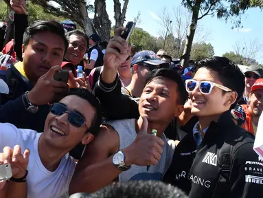 Pebalap Manor F1 Team, Rio Haryanto bertemu fans yang telah menunggu untuk menyaksikan balapan perdana Formula One Australian Grand Prix, Melbourne, Minggu (20/3/2016). (AFP/Paul Crock)