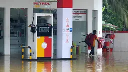 Seorang pekerja melewati halaman SPBU yang banjir akibat hujan lebat di Pugoda, Senin (16/5). Banjir dan tanah longsor yang melanda Sri Lanka memaksa puluhan ribu warga mengungsi dari rumah mereka, kata pejabat setempat. (Ishara S.KODIKARA/AFP)