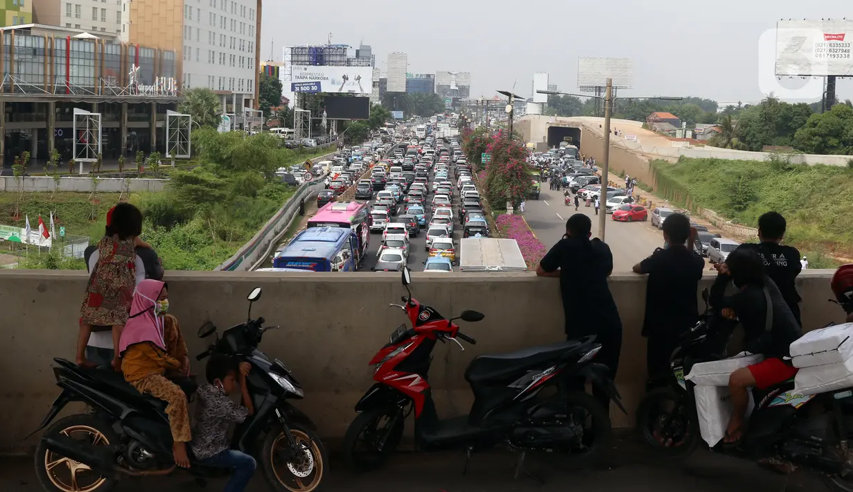 Warga melihat kendaraan terjebak kemacetan panjang di tol yang mengarah ke Bandara Soekarno-Hatta (Soetta), Tangerang, Banten, Selasa (10/11/2020). Kemacetan terjadi karena adanya penyambutan kepulangan pimipinan Front Pembela Islam (FPI) Rizieq Shihab. (Liputan6.com/Angga Yuniar)