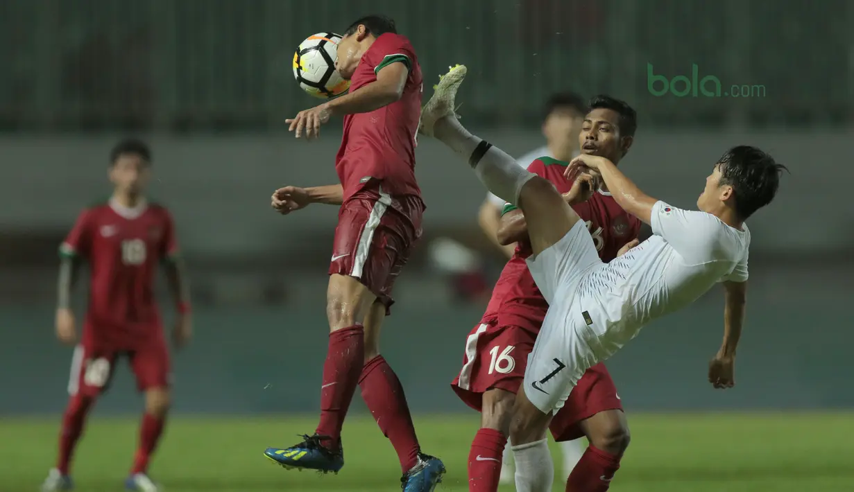 Aksi pemain Timnas Indonesia, Ricky Fajrin (kiri) menghalau bola dari pemain Korea Selatan U-23 pada laga uji coba di Stadion Pakansari, Bogor, (23/6/2018).  Indonesia U-23 kalah 1-2 dari Korea U-23. (Bola.com/Nick Hanoatubun)