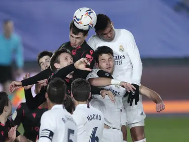 Para pemain Real Madrid dan Real Sociedad melompat berebut bola saat pertandingan lanjutan La Liga Spanyol di stadion Alfredo di Stefano di Madrid, Spanyol, Selasa (2/3/2021). Real Madrid bermain imbang atas Real Sociedad 1-1. (AP Photo/Bernat Armangue)