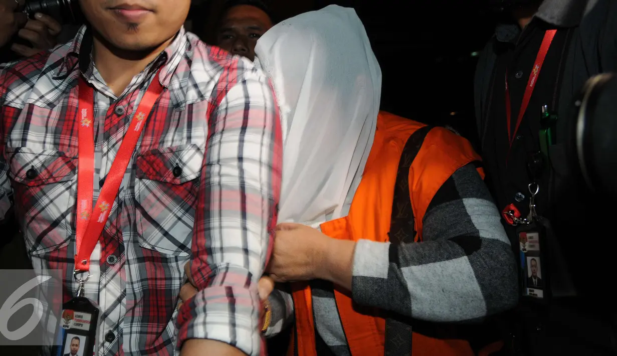 Bupati Klaten Sri Hartini menutupi wajahnya usai di periksa Komisi Pemberantasan Korupsi (KPK), Jakarta, Sabtu (31/12). Komisi Pemberantasan Korupsi menetapkan Bupati Klaten Sri Hartini (SHT) sebagai tersangka kasus suap. (Liputan6.com/Helmi Affandi)