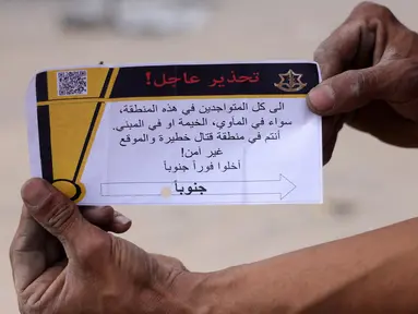 Seorang pria Palestina memegang selebaran yang dibagikan oleh tentara Israel pada 22 Mei 2025. (BASHAR TALEB/AFP)