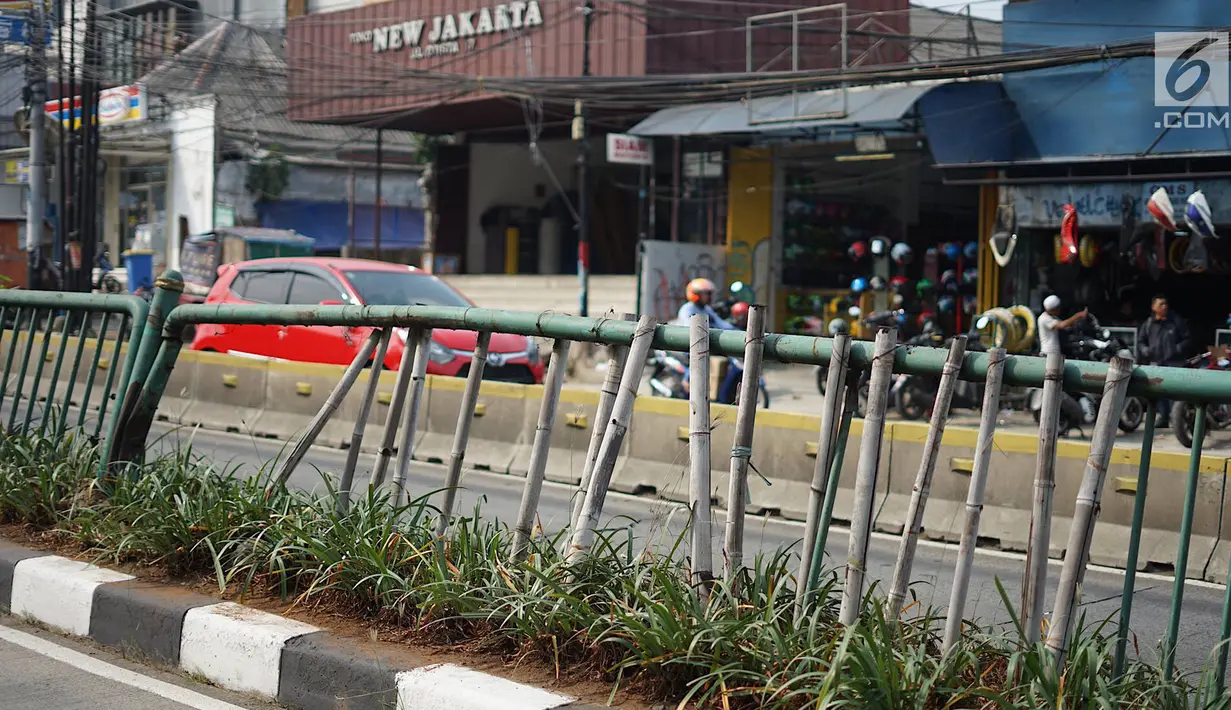 Sejumlah bambu menopang pagar pembatas jalur transjakarta di Jalan Otista Raya, Jakarta, Jumat (5/7/2019). Meskipun telah lama rusak, pagar besi berjeruji yang berfungsi sebagai pembatas agar orang tidak menyeberang secara sembarangan itu belum juga diperbaiki. (Liputan6.com/Immanuel Antonius)