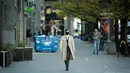 Seorang pria yang mengenakan masker berjalan di sepanjang Jerusalem Avenue yang hampir kosong di Warsawa tengah, Polandia (20/4/2020). Pemerintah Polandia telah melonggarkan beberapa kebijakan pembatasan terkait pandemi COVID-19 pada Senin (20/4). (Xinhua/Jaap Arriens)
