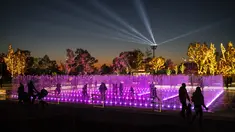 Pengunjung berjalan di dalam pertunjukan cahaya dan air mancur yang ditampilkan menjelang perayaan Natal di Experience Park, di distrik pesisir Hellenikon di Athena, Senin (20/12/2021).  (AFP/Angelos Tzortzinis)