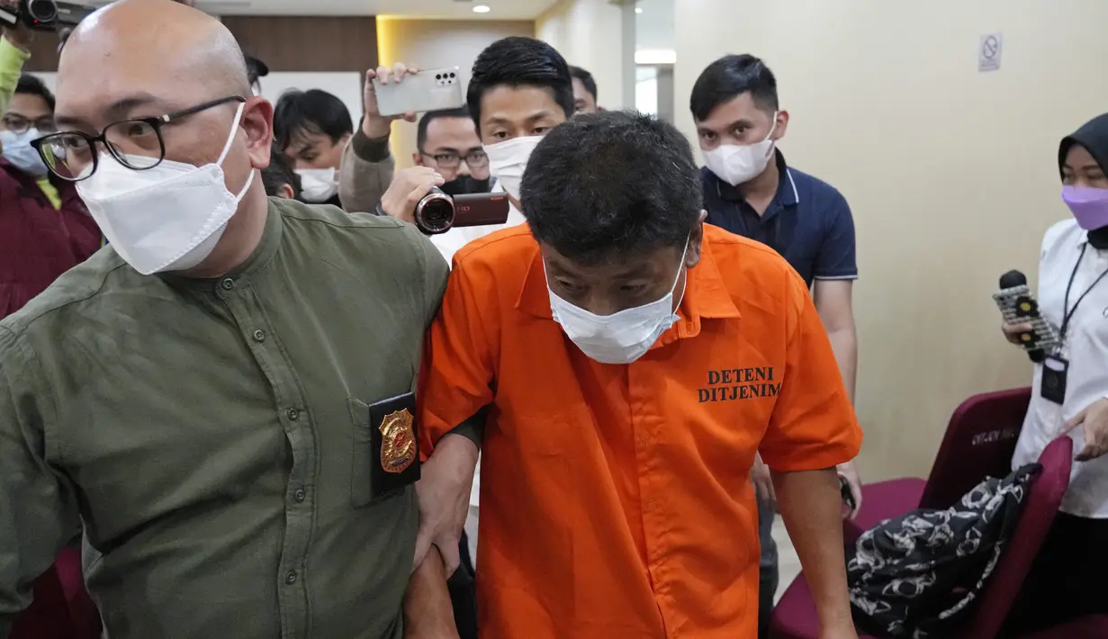 Petugas imigrasi mengawal Mitsuhiro Taniguchi (47) usai konferensi pers di Kantor Imigrasi, Jakarta, Indonesia, Rabu (8/6/2022). "MT (Mitsuhiro Taniguchi) sudah diamankan oleh pihak imigrasi setelah pihak Jepang mencabut passport yang bersangkutan," kata Kepala Divisi Humas Polri Irjen Dedi Prasetyo kepada wartawan, Rabu (8/6/2022). (AP Photo/Achmad Ibrahim)