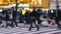 Orang-orang yang memakai masker berjalan di sekitar persimpangan Shibuya Tokyo, Jepang, Senin (29/11/2021). Penutupan pintu untuk warga negara asing ke Jepang hanya  bersifat sementara hingga diperoleh informasi lanjutan tentang varian Omicron. (AP Photo/Kiichiro Sato)