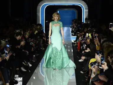 Model AS, Gigi Hadid berjalan membawakan koleksi terbaru Moschino di panggung runway Milan Fashion Week 2018, Rabu (21/2). Gigi terlihat cantik dengan gaun warna hijau muda beraksen sparkling di bagian lengan dan leher serta kakinya. (Miguel MEDINA/AFP)