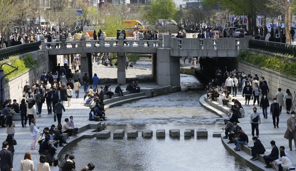 Orang-orang yang memakai masker berjalan di sepanjang area publik Cheonggye Stream di Seoul, Korea Selatan, Jumat (15/4/2022). Korea Selatan atau Korsel akan menghapus sebagain besar pembatasan covid-19 pekan depan menyusul lonjakan kasus Omicron yang mulai berkurang (AP Photo/Ahn Young-joon)