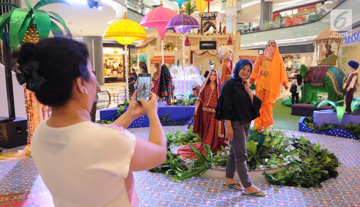 Pengunjung berpose di dekat dekorasi tematik Ramadan di pusat perbelanjaan, Jakarta, Selasa (30/5). Saat bulan Ramadan banyak warga menghabiskan waktu di Mall sembari menunggu berbuka puasa. (Liputan6.com/Gempur M Surya)