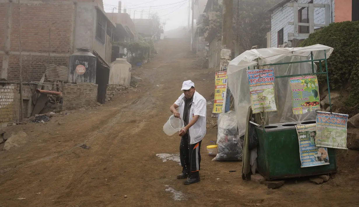 Ramon Gutierrez mencuci tangannya sambil bersiap untuk menjual pure apel panas yang disebut "mazamorra" pada hari resmi pertama musim dingin, di lingkungan Ticlio Chico di pinggiran Lima, Peru, Selasa (21/6/2022). Suhu di ibu kota adalah yang terendah dalam 25 tahun, menurut National Layanan Meteorologi dan Hidrologi Peru. (AP Photo/Martin Mejia)