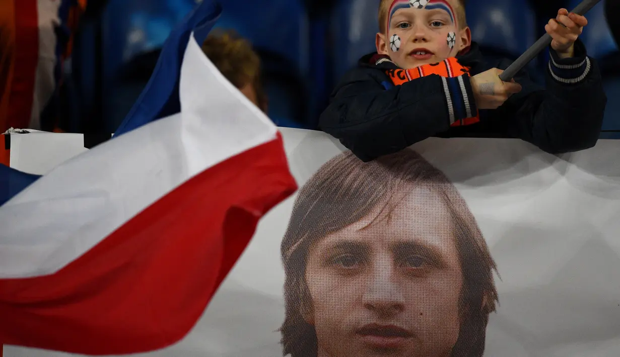 Suporter cilik Belanda dengan spanduk bergambar legenda sepak bola dunia, Johan Cruyff, dalam pertandingan antara Belanda melawan Prancis di Stadion Amsterdam Arena, (25/3/2016). Cruyff meninggal dunia dalam usia 68 tahun. (AFP/Franck Fife)