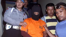 Petugas kepolisian mengawal tersangka kasus pembunuhan, Putu Astawa di kantor Polisi Bali, Denpasar (18/9). Astawa membunuh pasutri asal Jepang, Matshuba Hiroko yang berusia 70 tahun dan Matshuba Norio yang berusia 73. (AP Photo/Firdia Lisnawati)
