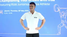 Lifter Indonesia yang lolos ke Olimpiade Paris 2024 dan terpilih menjadi bagian Tim Visa, Rizki Juniansyah berpose saat acara konferensi pers di The Residence OnFive, Grand Hyatt, Jakarta, Kamis (16/5/2024). (Bola.com/Syahkist Afi)
